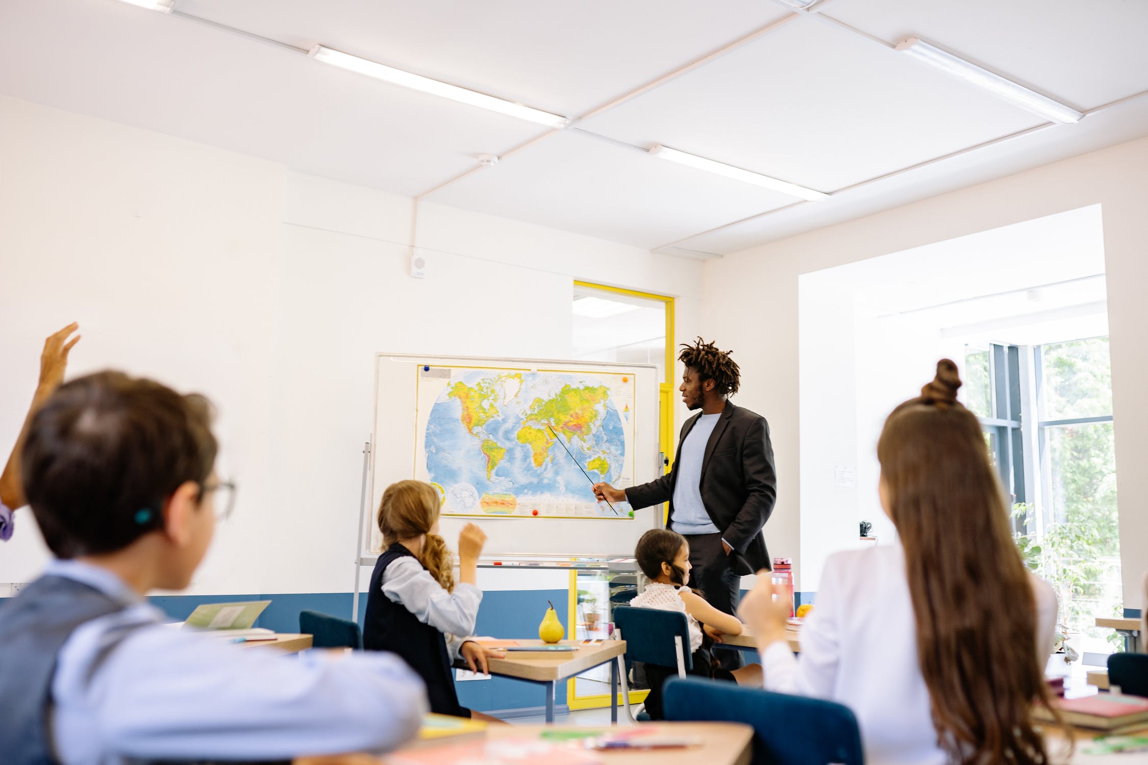 Teacher and students in classroom looking at a map