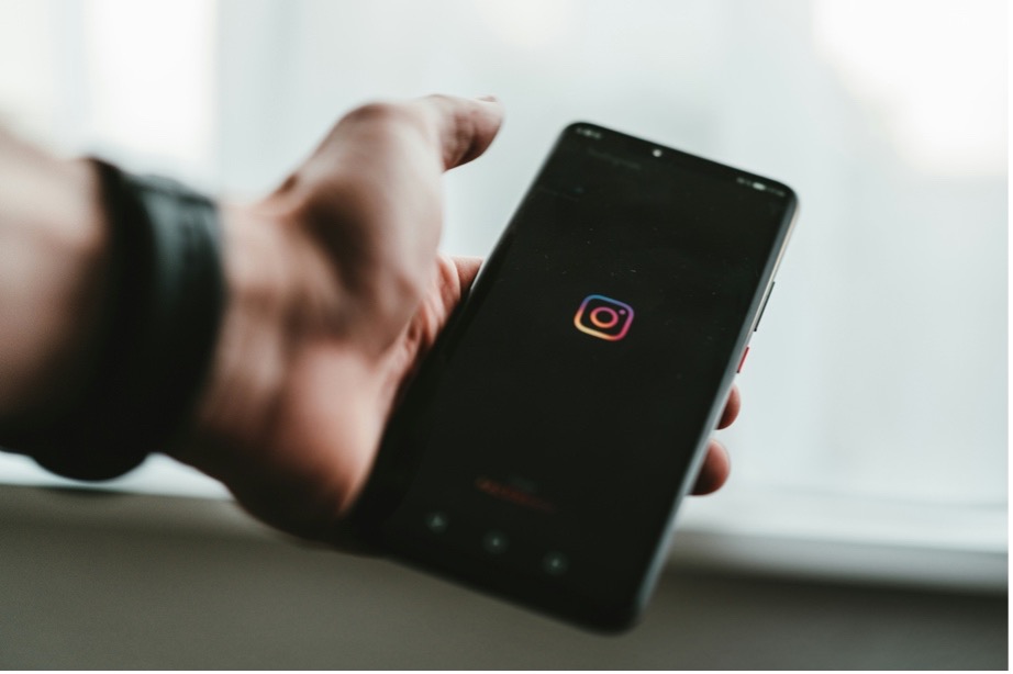 person holds out phone with instagram logo