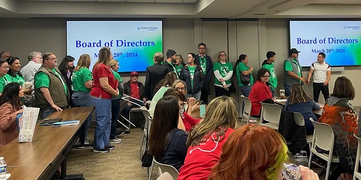SVFT members holding signs at a Salinas Valley Health board meeting